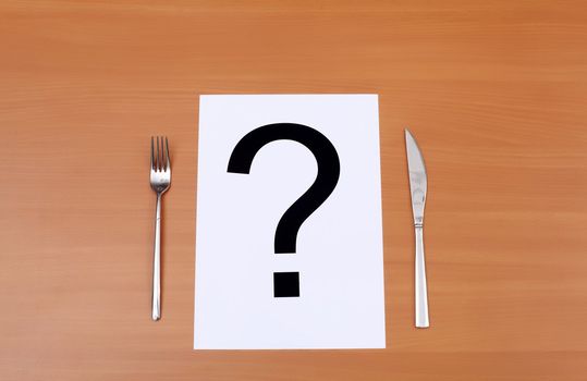 Metal knife and fork on the table and question mark