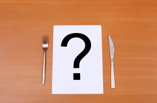 Metal knife and fork on the table and question mark