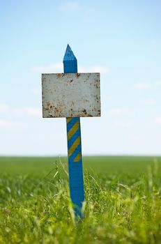 Weather-beaten sign on a grassy land plot