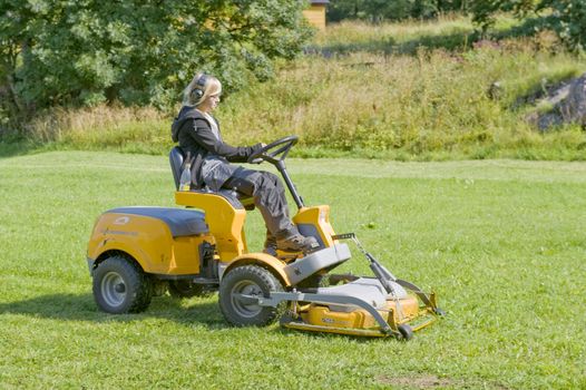 The young woman does the macine grass trim