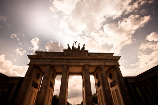 Low angle view of the Brandenburg Gate, or Brandenburger Tor, in Berlin against a dramatic evening sky with clouds