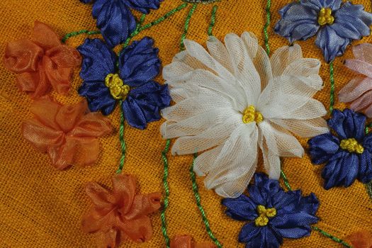 Blue chicory, white 
chrysanthemum and orange flowers 
are embroidered by tapes on bright yellow linen fabric
