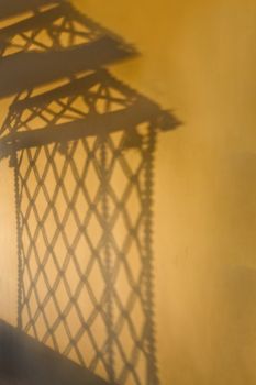 Portrait of a shadow thrown by a hammock style hanging from the ceiling, a rope chair on a balcony, veranda or interior room. The shadow is cast by early morning sun falling on the subject. Location of shot was Dwarka, Gujarat, India but fairly generic on the continent