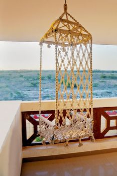 Texture of horizon line through a hammock style rope chair hanging from the ceiling on a balcony. Generic shot location hotel near Dwarka, Gujarat, India