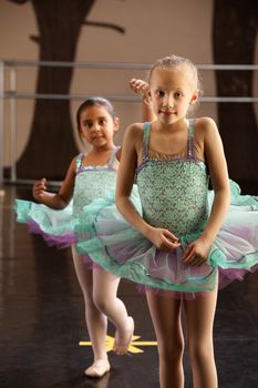 Two children in ballet dresses standing in a dance studio