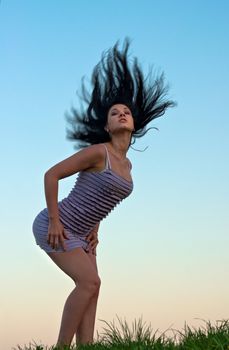 Girl with disheveled hair against evening sky.