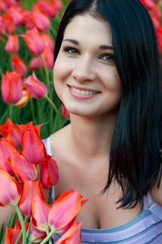 Brunette girl close-up with bright red tulips.