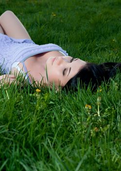 Woman lies on her back in grass at night.