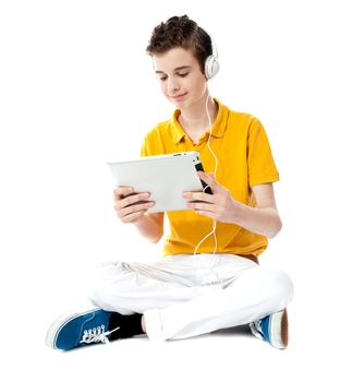 Boy sitting with crossed legs watching video on tablet