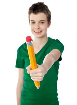 Young boy showing big yellow pencil to camera