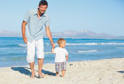 Father and son having fun on tropical white sand beach