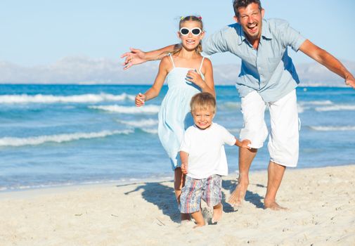 Happy family of three sitting and having fun on tropical beach