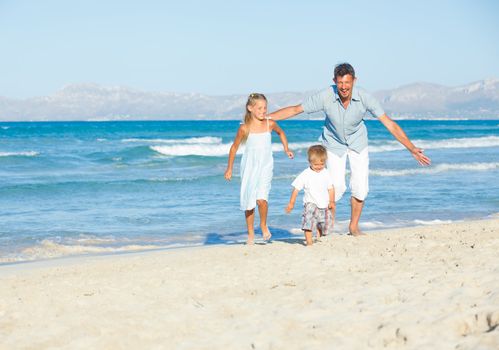 Happy family of three sitting and having fun on tropical beach