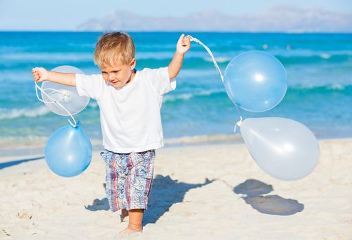 Cute little boy plays with ballons on the beach