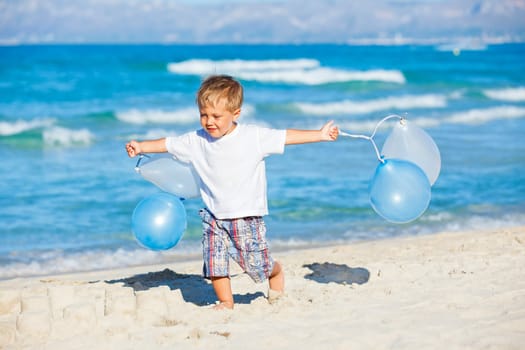 Cute little boy plays with ballons on the beach