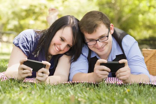 Attractive Young Couple at the Park Texting on Their Smart Phones Together.