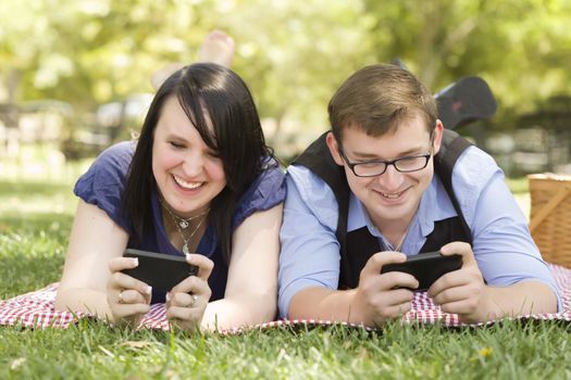 Attractive Young Couple at the Park Texting on Their Smart Phones Together.