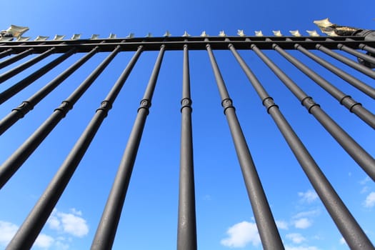 Huge black iron fence closes the blue sky