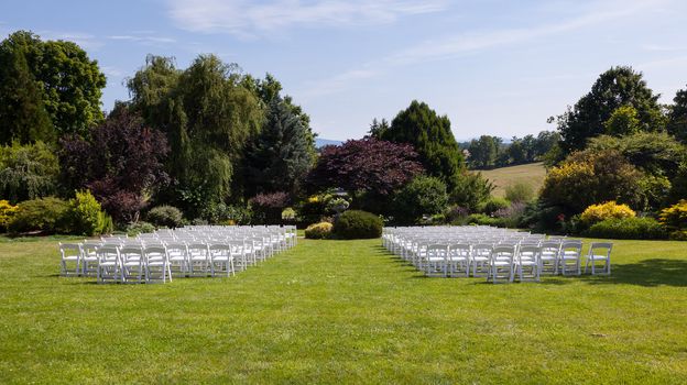 Rows of formal white wooden wedding chairs set up for a wedding or concert