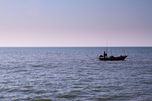 The silhouette of a fisherman with his boat in the sea