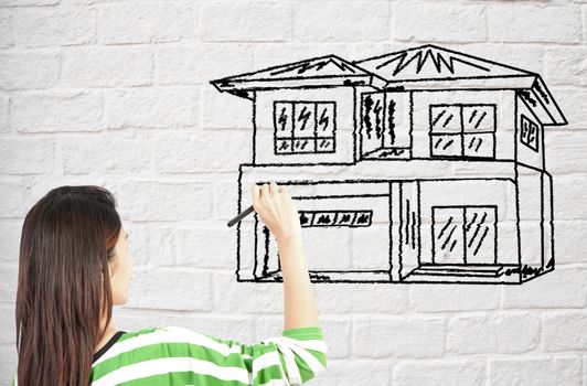 woman draw house on brick wall