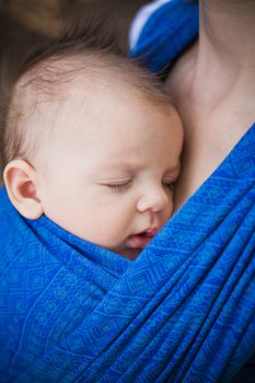 sleeping newborn baby in the baby carrier