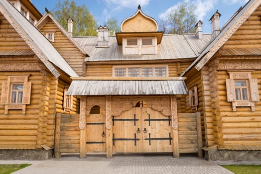 Wooden log house with decorated windows and gate, Russian traditional architecture.