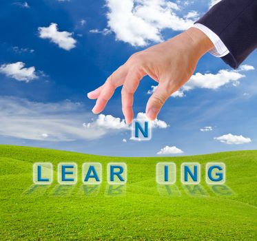business man hand and learning word on green grass meadow