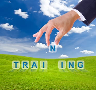 business man hand made training word buttons on green grass meadow