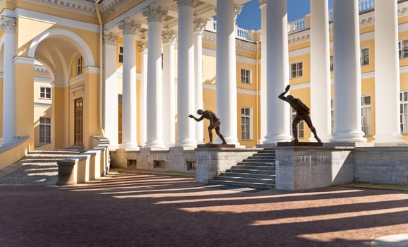 Classical building of Aleksandrovsky palace with white columns and man sculptures