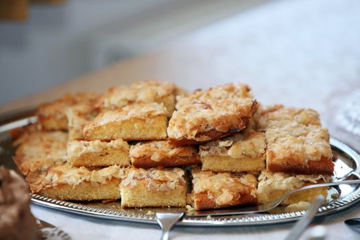 Plate of delicious freshly baked almond cookies topped with flaked almonds on display on a buffet table for dessert