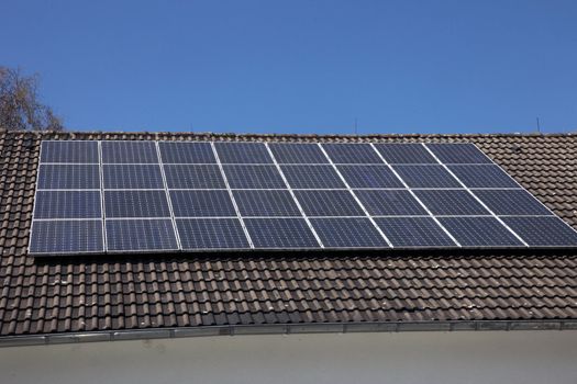 An array of photovoltaic solar panels mounted on a house roof to supply renewable domestic electricity by converting the radiant energy of the sun