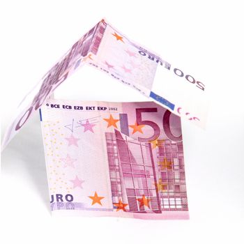 Conceptual image of a money house with walls and roof made of folded of 500 Euro notes isolated on white