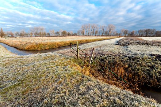 view on typical Dutch flat landscape with fence during the winter