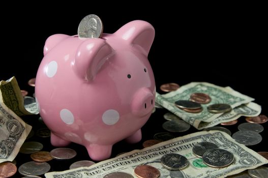 Pink polka dot piggy bank surrounded by cash and coins