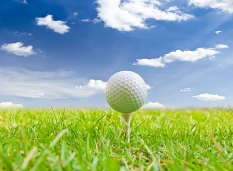 golf ball and tee grass against blue sky