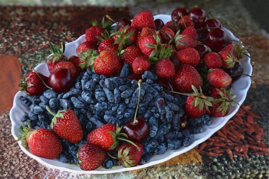 honeysuckle, strawberries and cherries on a plate