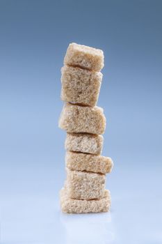 Vertical stack of brown sugar cubes on blue.