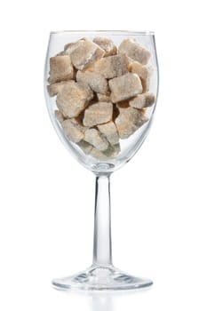 Wine glass filled with brown sugar cubes. Isolated.