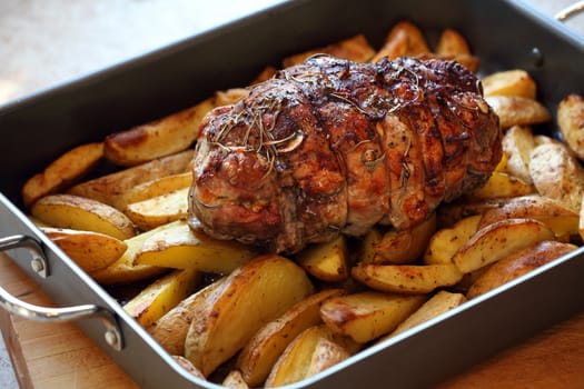 Photo of a lamb roast with potatoes in a roasting pan fresh out of the oven.