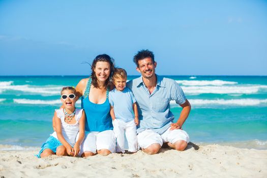 Family of four having fun on tropical beach