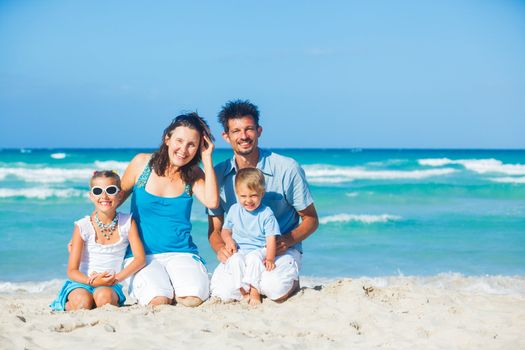 Family of four having fun on tropical beach