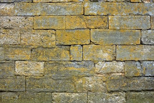 Ancient stone wall with large blocks partially covered with green lichen