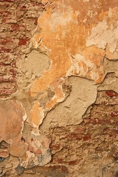 Fragment of old brick wall with ragged plaster and multiple whitewash layers