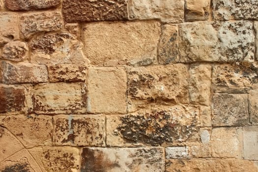 Medieval stone wall with large blocks with ragged layers of paint