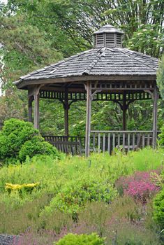 Old wooden gazebo in green botanical garden