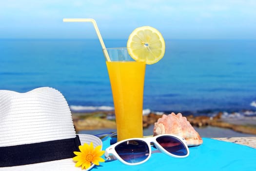 yellow fruit cocktail and a white hat on the background of a beautiful sea landscape
