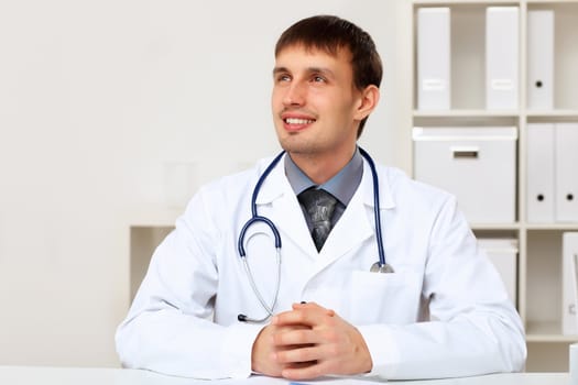 Young male doctor in white uniform at workplace