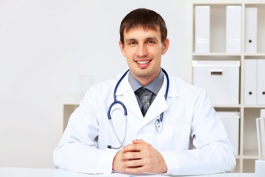 Young male doctor in white uniform at workplace