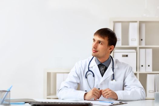 Young male doctor in white uniform at workplace